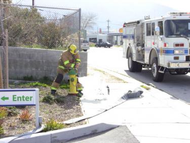 A Kern County firefighter hooks up to a fire hydrant at the entrance to Holiday Inn Express Saturday afternoon. [photo by The Mountain Enterprise]