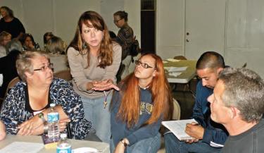 Michi Knight reminds tables that the goal is to find positive solutions to school challenges (l-r) Chandra Mead, FFA advisor Nicole Patterson, parent and coach Jose Flores, and a concerned neighbor.