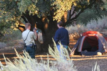 Crime investigators examine the area around the tent before examining the body inside. [Meyer photo]

