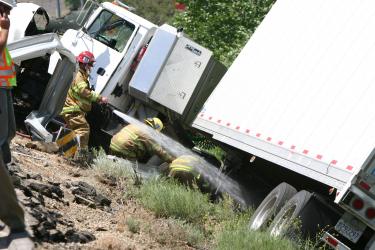Kern County Fire crew members from Station 55 and 56 work to remove debris from around a big rig that crashed in Gorman on Thursday, May 28. [Meyer photo]


