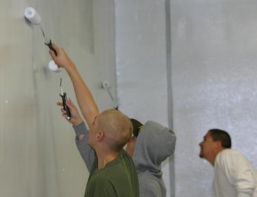 Football players from both the varsity and junior varsity teams worked alongside parents and coaches to paint the FMHS workout room.