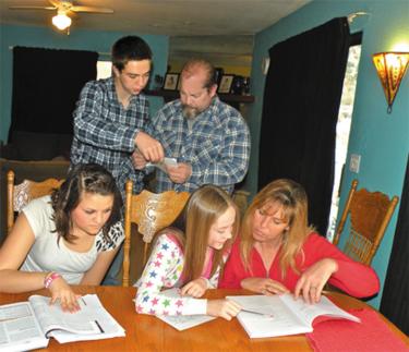 (Back) Joey, 17 and his dad Benjamin Houghton, (front, l-r), family friend Katelyn Ciotto, 16, Sarah, 12 and mom Monica Houghton look over the students’ homework assignments on Sunday, Jan. 30 after taking time to explain what they know about the demonstration and the San Miguel Trail bus stop accident.