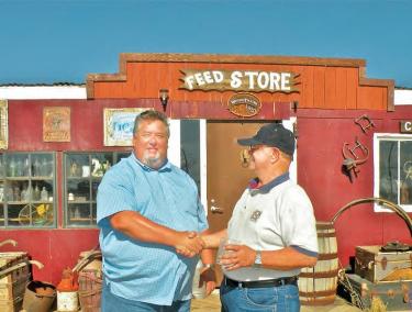 First Solar, Inc. Construction Manager Gary Baumeister shakes hands with Richard Skaggs on July 10 at a barbecue and informal job fair for the neighborhood. They are standing in front of the whimsical &quotHiker Town" Pacific Coast Trail hostel for hikers maintained by Mr. and Mrs. Skaggs. Skaggs is president of the Oso Town Council which is seeking to move toward more unity between Western Antelope Valley rural town councils.