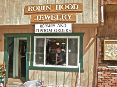 Kip Storz is seen sweeping up glass shards through the shattered front window of Robin Hood Jewelry in Pine Mountain Village on Friday, Aug. 12 at about 10 a.m.