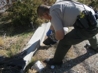 Deputy Isaac Ramos finds plastic bag containing a gun and a note on the grounds of The Mountain Enterprise on Monday, Dec. 26. [Mountain Enterprise photo by Pam Sturdevant]