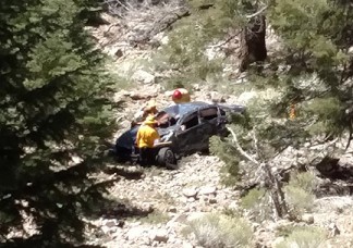 This vehicle rolled off the side of Cerro Noroeste Road and ended up about 1,000 feet down. Four firefighters are shown rescuing a dog that was trapped inside the car. [photo by Al Tapia]