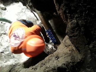An FPPUD employee installs clamps to stop the broken water line from leaking. [photo by Jonnie Allison]