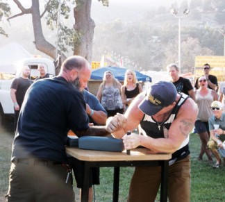 Patrick Hirst (above, right) won the ‘right handed’ Fiesta Days arm wrestling contest as the crowd cheered. Steve Swaim (left) won the left-handed contest. The challenge is out for more aspiring champs next year, men and women. [photo by Jeff Arnburg]