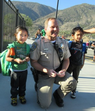 Fort Tejon CHP Officer Brian Moore was handing out 'Junior Officer' badges as kids arrived for school. [photo by Gary Meyer, The Mountain Enterprise]