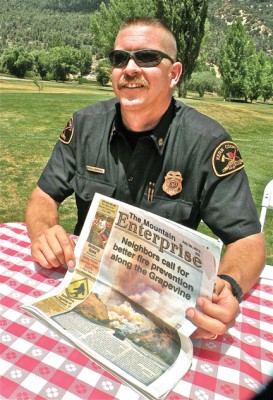 Kern County Fire Chief Brian Marshall holds a copy of The Mountain Enterprise full of questions about who is responsible to remove fire hazards along the Grapevine. [photo by Patric Hedlund]