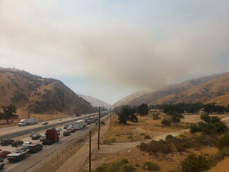 [Northbound I-5 traffic backs up on Sunday afternoon, June 27, due to a fire six miles ahead at Grapevine Road. In the photo, the fire is seen reaching the hills above Tejon Ranch headquarters and El Tejon School. Photo by Elke Heitmeyer]