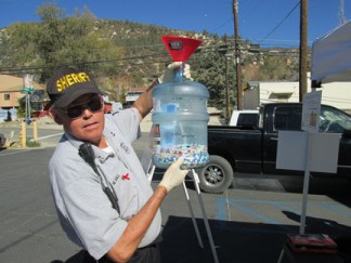 Sheriff's Volunteer Mike Hall shows the bottle of pills collected by 11 a.m. at the Drug Take Back event. [photo by Gary Meyer]