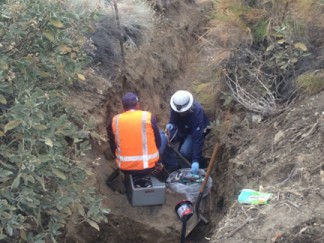 Repairmen work in a storm drainage ditch to fix the severed telephone line. [photo by Gary Meyer]