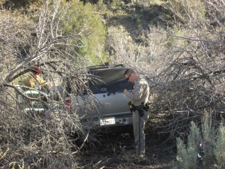 The silver Chevy SUV came to rest in vegetation on the creek side of the hill. It did not appear to have rolled over. The driver was extracted from the car and put on a stretcher.  [Gary Meyer photo]