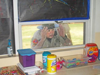 Kern Co. Sheriff’s Sergeant Mark Brown looks through a classroom window to see if any children are there. [photo by Gary Meyer]