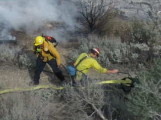 Fire fighters knock down the flames in the early stages of the fire. [photo by Gary Meyer]