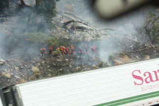 Marlena Meigs caught a glimpse of firefighters over the passing traffic as the Fort fire reached Interstate 5 on Friday, July 8. [photo by Marlena Meigs]