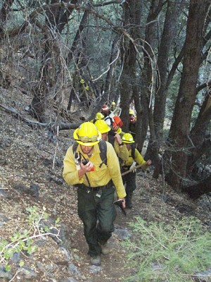 About 20 US Forest Service strike team members hike up the trail from the top of Bernina Drive in Pine Mountain, before reaching a steep incline rising from a ravine, just below the fire. [photo by Gary Meyer]