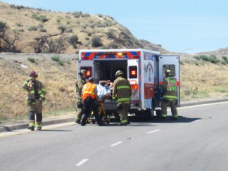 The driver is assisted after walking to to the waiting ambulance. [photo by Gary Meyer]
