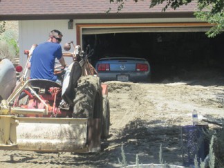 Caleb Kanke clears mud and debris from Gil Karson’s property on Johnson Road in Frazier Park. Mud was up to the eaves at the back of the home. [photo by Gary Meyer]