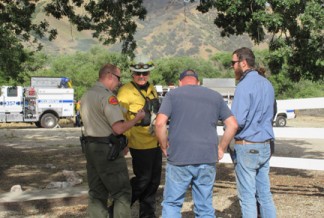 (l-r) A Kern County sheriff's deputy speaks with Kern County Fire Department Battalion Chief Kirk Kushen and witnesses about the fire. [photo by Gary Meyer, The Mountain Enterprise]