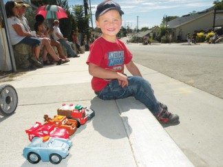 James Crippen, 3 ready and waiting in 2013 for the Fiesta Days Parade to start down Mt. Pinos Way, toys all lined up in a row. [photo by Patric Hedlund]