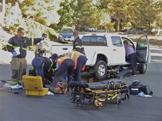 Crash site on Mil Potrero Highway, with the motorcycle rider being attended by paramedics from Fire Station 58. The Yamaha motorcycle slid under the truck, which was  making a left turn into Pine Mountain Village at Pine Circle Drive. Double click on photo to enlarge. [Patric Hedlund photo for The Mountain Enterprise]