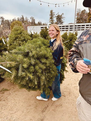 FFA volunteer helps customer with a tree to be package
